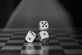 Black and white dice on a checkered board with dramatic lighting