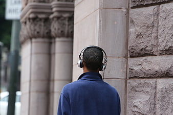 Man with Headphones Standing by Stone Wall
