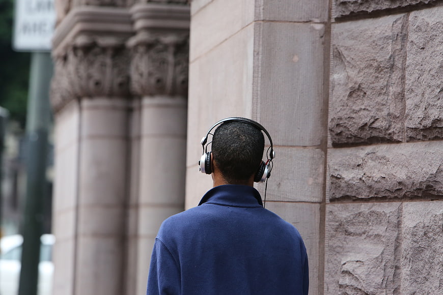 Man with Headphones Standing by Stone Wall