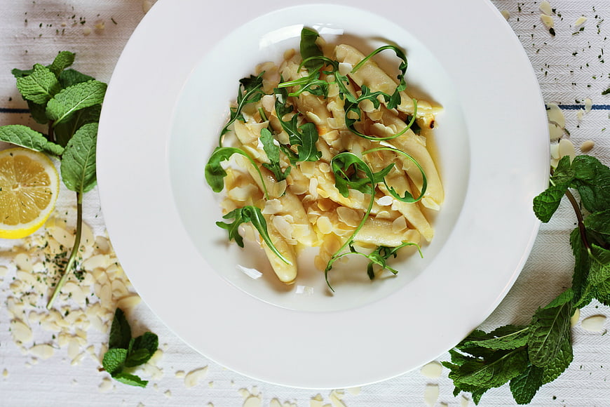 Overhead view of creamy pasta with almonds and arugula