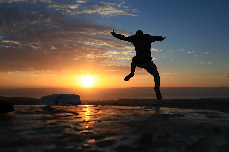 Silhouette of man jumping in joy at sunset