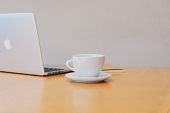 White Coffee Cup And Silver Laptop On Wooden Desk