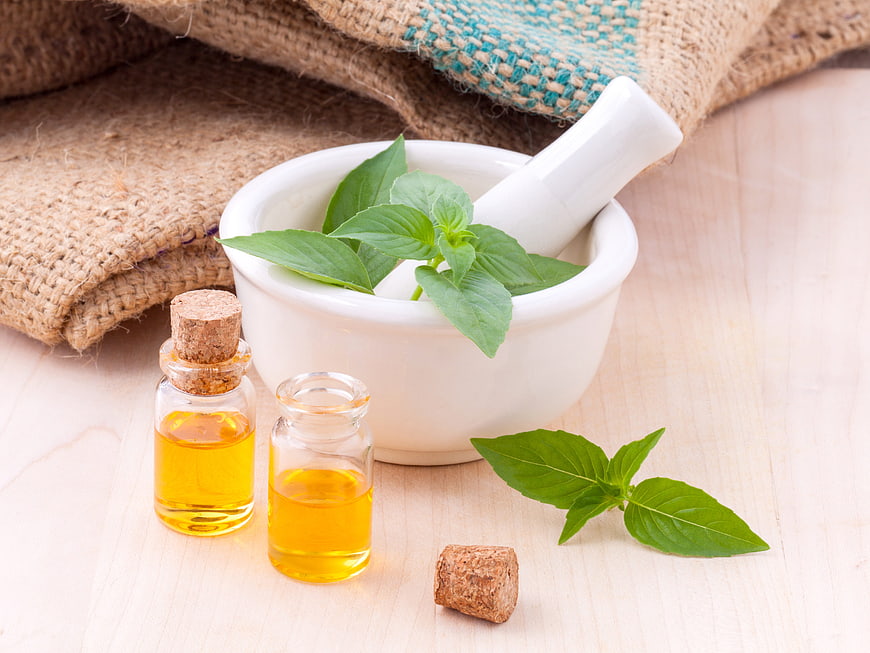 Fresh Basil Leaves and Essential Oil in Mortar and Pestle