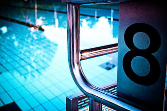 Close-up of swimming pool lane marker number 8 with metal ladder
