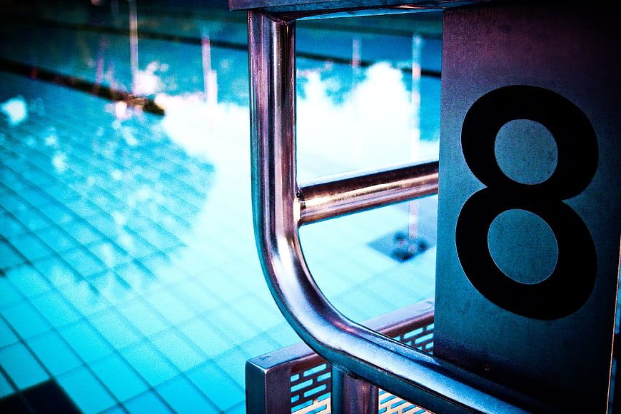 Close-up of swimming pool lane marker number 8 with metal ladder
