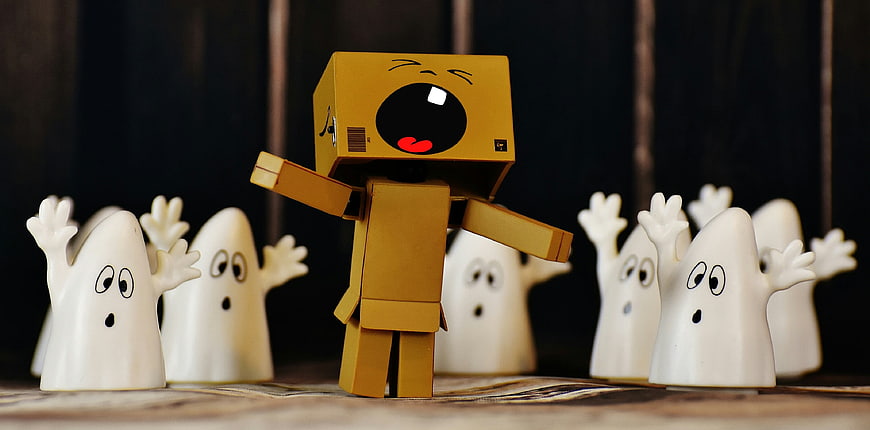 Cardboard box character crying surrounded by small white ghosts