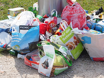 Pile of trash bags and waste on gravel ground