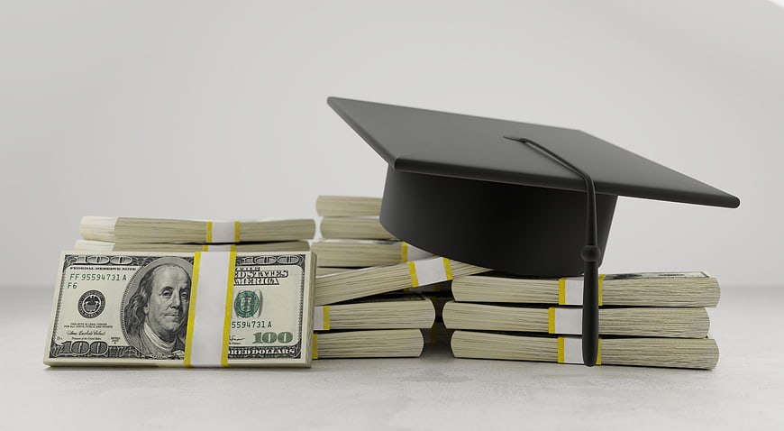 Graduation Cap Resting On Stacks Of US Dollar Bills