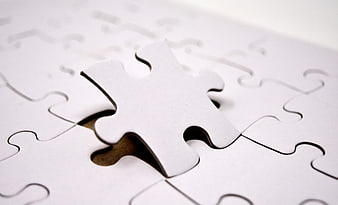 White puzzle piece hovering over missing spot in jigsaw puzzle