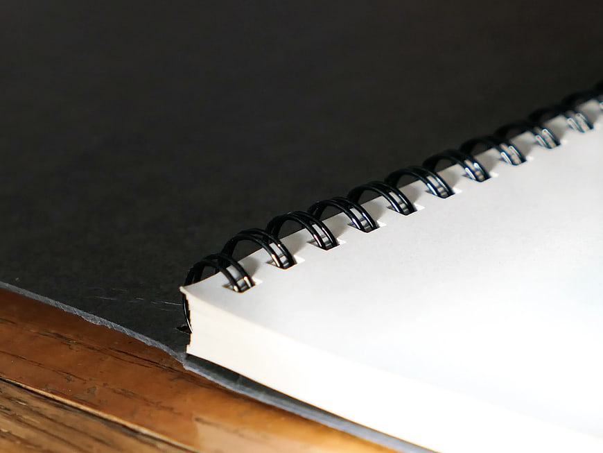 Close-up of spiral notebook on dark surface