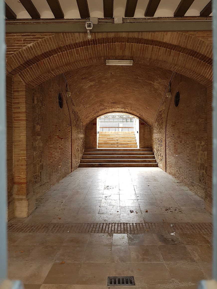 Arched brick tunnel leading to bright exit in Valencia