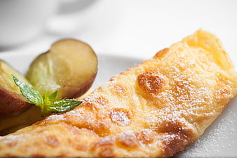 Close-up of golden apple strudel with powdered sugar and fresh fruit