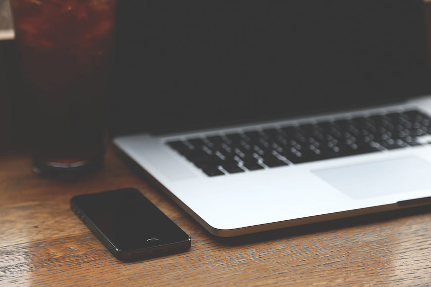 Black Smartphone and Silver Laptop on Wooden Desk