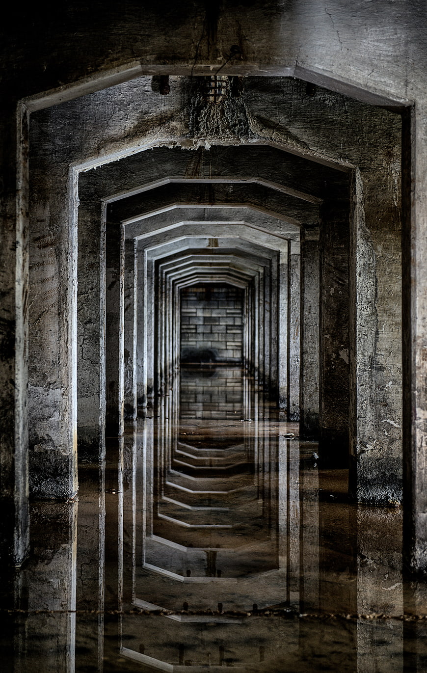 Symmetrical concrete tunnel with water reflection and leading lines