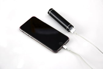 Black smartphone charging with portable power bank on white background