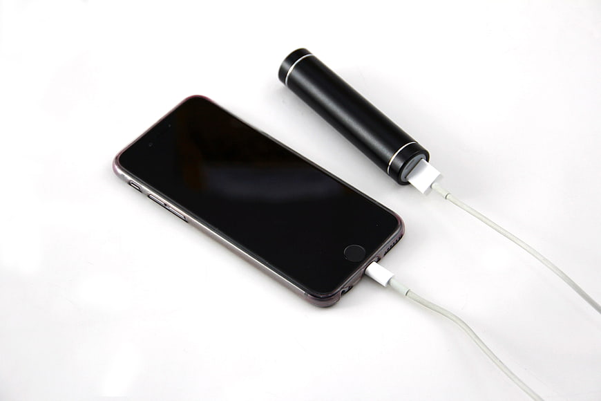 Black smartphone charging with portable power bank on white background