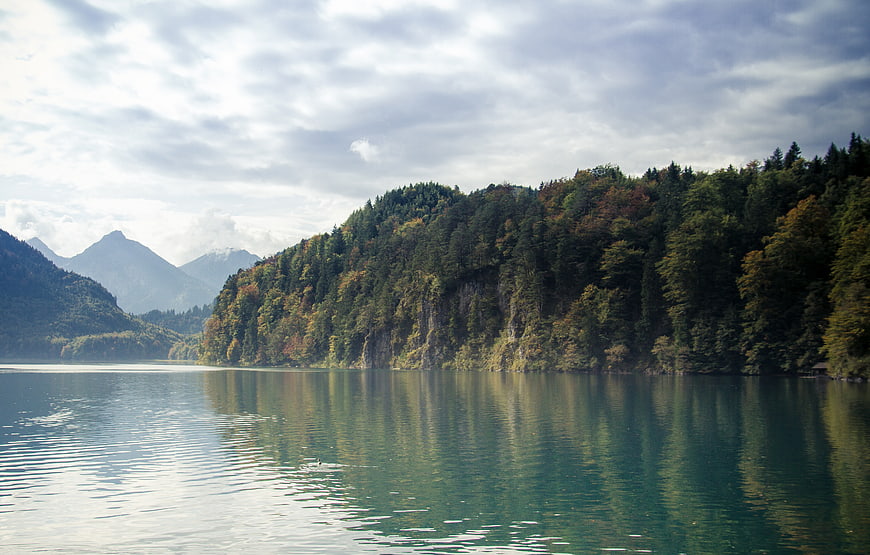Serene Alpine Lake with Forested Hills and Mountain Reflections