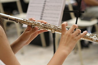 Close-up of hands playing a silver flute in a music classroom