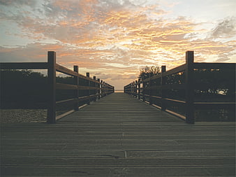 Wooden Boardwalk Pier at Sunset with Dramatic Clouds