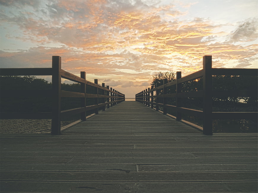 Wooden Boardwalk Pier at Sunset with Dramatic Clouds