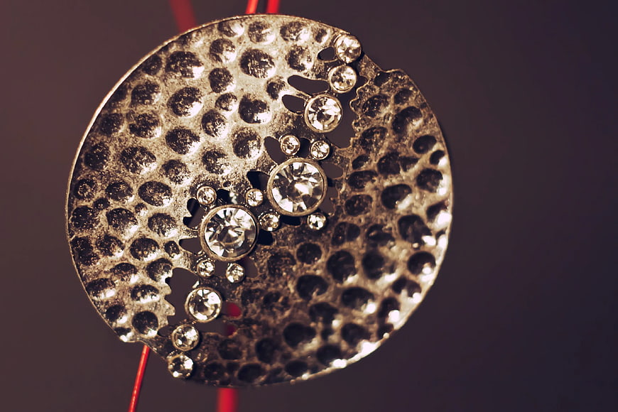 Close-up of textured silver jewelry pendant with rhinestones