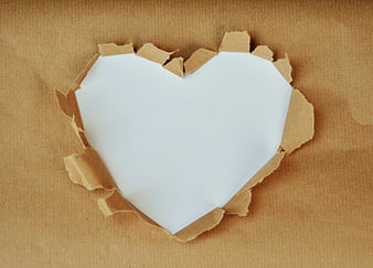 Heart-shaped cutout in brown paper revealing white background