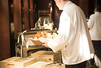 Chef serving basket of fresh bread rolls at buffet