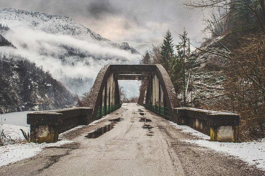 Snowy Concrete Arch Bridge in Winter Mountain Landscape