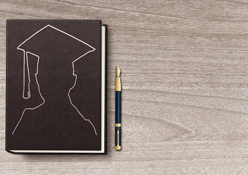 Graduation Cap Embossed Notebook and Fountain Pen on Wooden Table