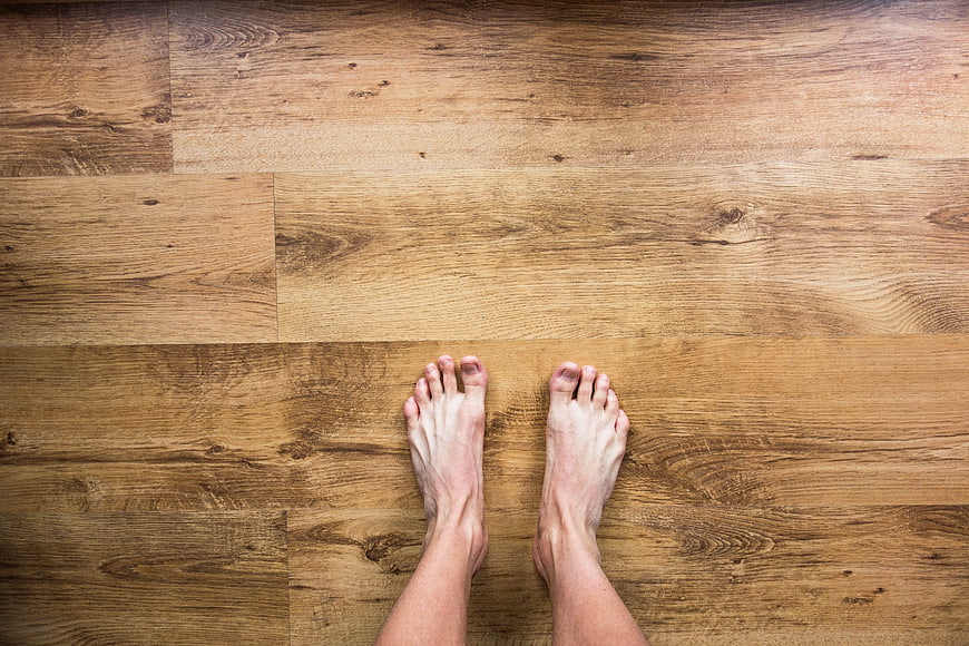 Bare feet standing on wooden floor top view