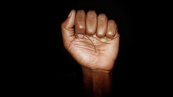 Black fist raised against dark background symbolizing power and resistance