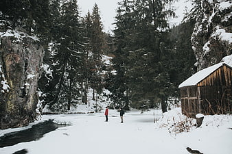 Couple standing on frozen river in snowy mountain forest