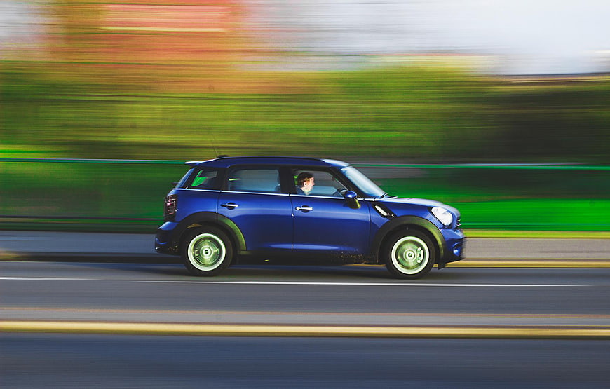 Blue Mini Cooper Driving Fast on Road with Motion Blur