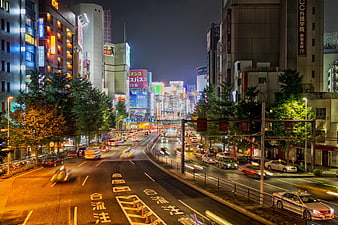 Tokyo Night Street Traffic With Neon Lights And Urban Buildings