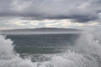 Dramatic Sea Waves Crashing Against Rocky Coast Under Stormy Sky
