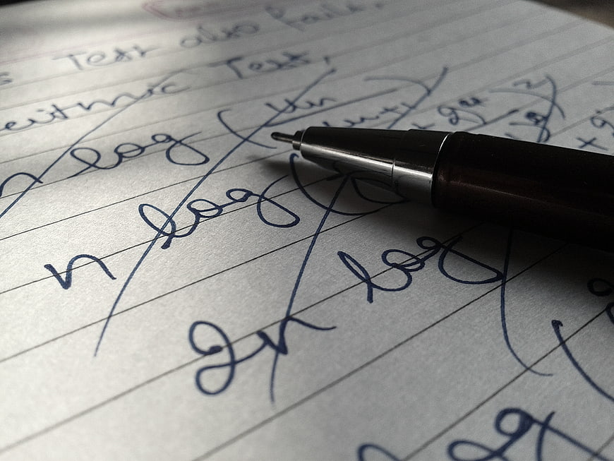 Close-up of handwritten math notes with pen on paper