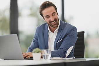 Happy businessman laughing while working on laptop in office