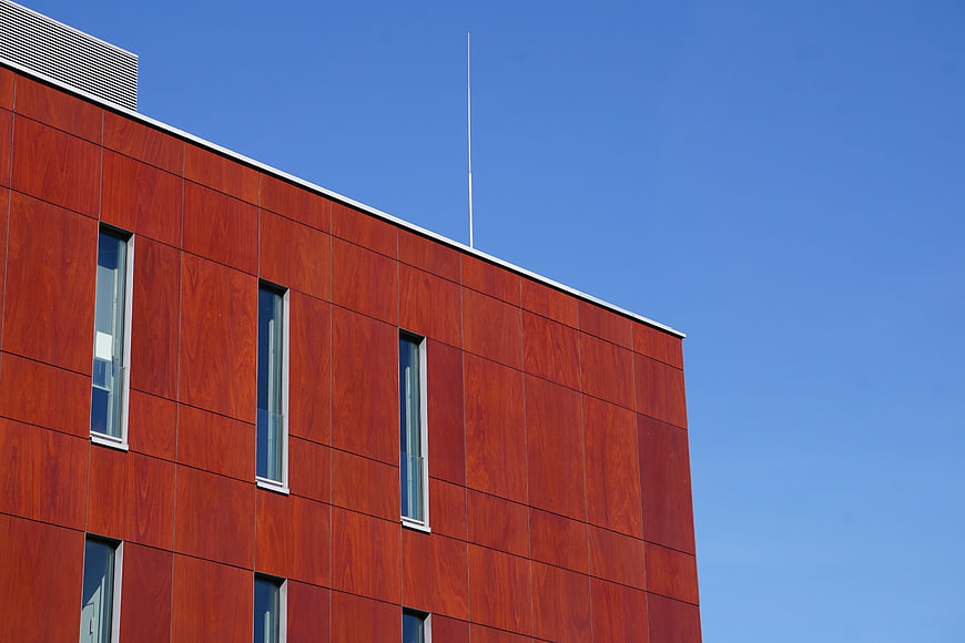 Modern Red Wood Clad Building Facade Against Blue Sky