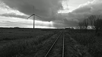 Black and white wind turbine and railroad tracks in field