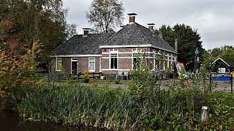 Traditional Dutch brick farmhouse by a canal in autumn