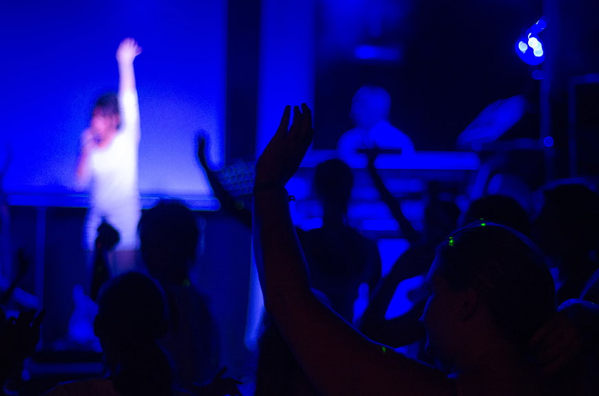 Woman singing on stage with raised hand in blue light