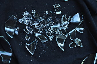 Shattered glass fragments on dark fabric surface
