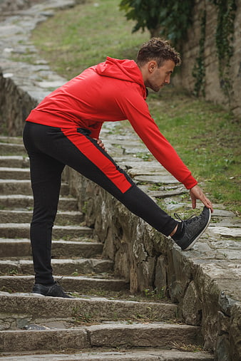 Athletic Man Stretching Leg on Stone Steps Outdoors