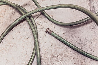 Green Garden Hose Coiled on Textured Concrete Surface