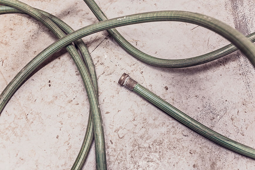 Green Garden Hose Coiled on Textured Concrete Surface