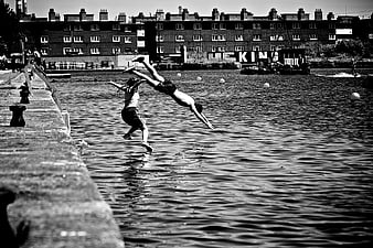 Two people diving into urban river in black and white
