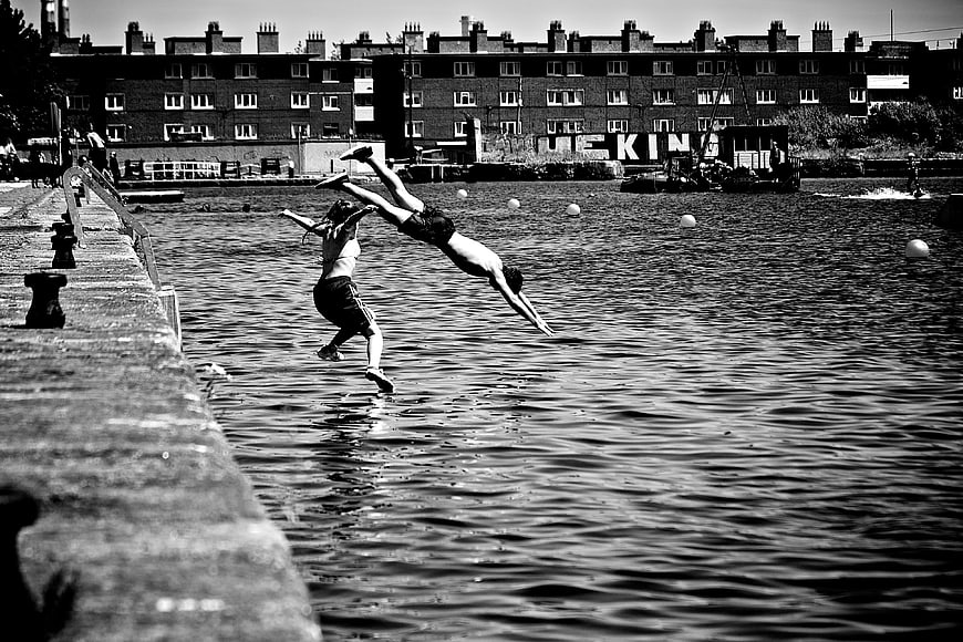 Two people diving into urban river in black and white