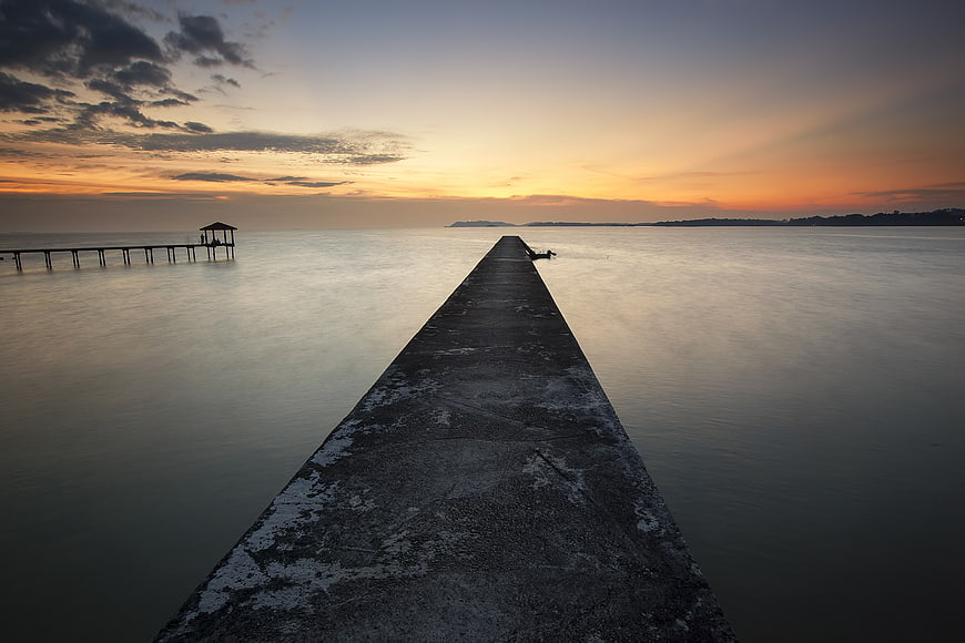 Long Exposure Concrete Pier at Sunset Over Calm Ocean