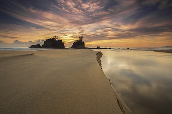 Serene Sunset Beach with Silhouetted Rock Formations
