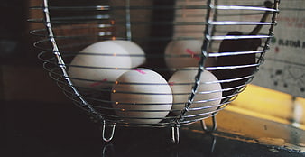 Fresh white eggs in a wire basket on a dark counter